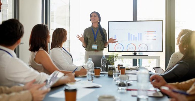 woman presenting data on a screen to her colleagues