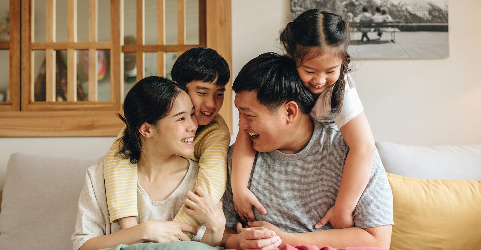 Family seated on the couch with the children hugging the parents
