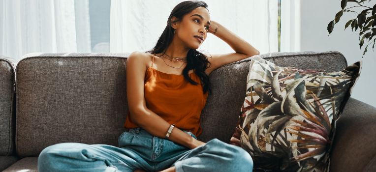 younger woman on couch thinking deeply