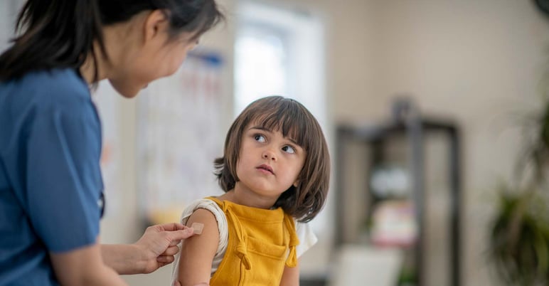 young child at the doctor's office looking at the nurse