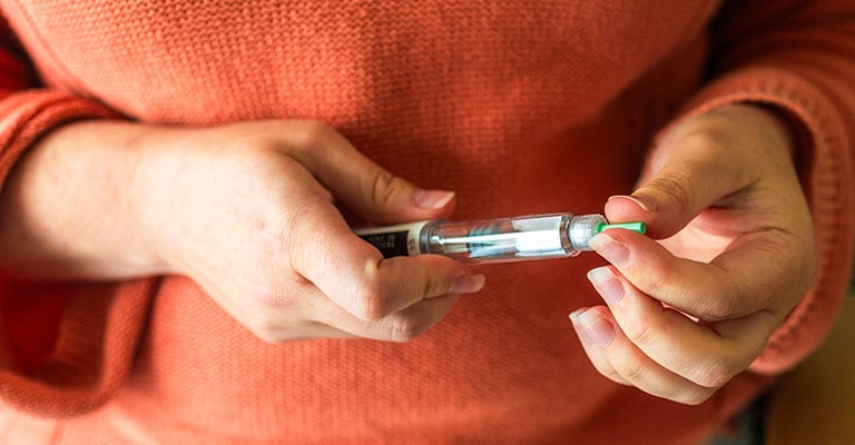 closeup of hands holding an injectable drug