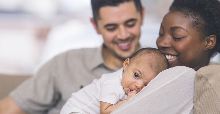 mother holding newborn with father looking on