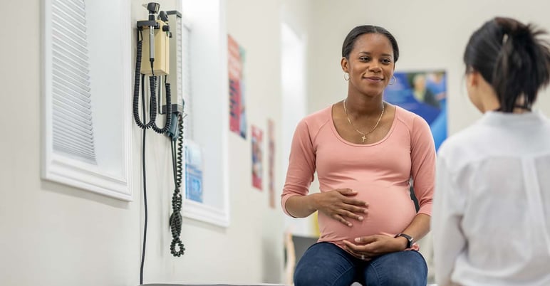 happy pregnant woman seated in exam room