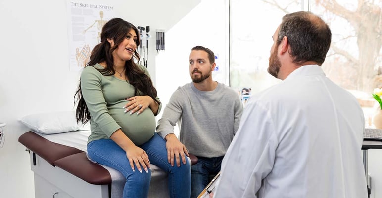 pregnant patient talking animatedly to her provider, with her partner looking on