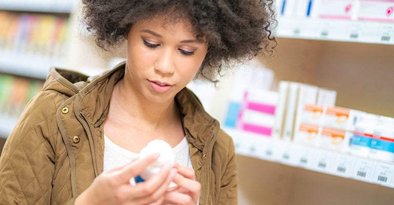 woman reading pill bottle at the pharmacy