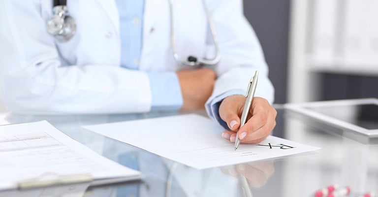closeup of a doctor's hand filling out paperwork