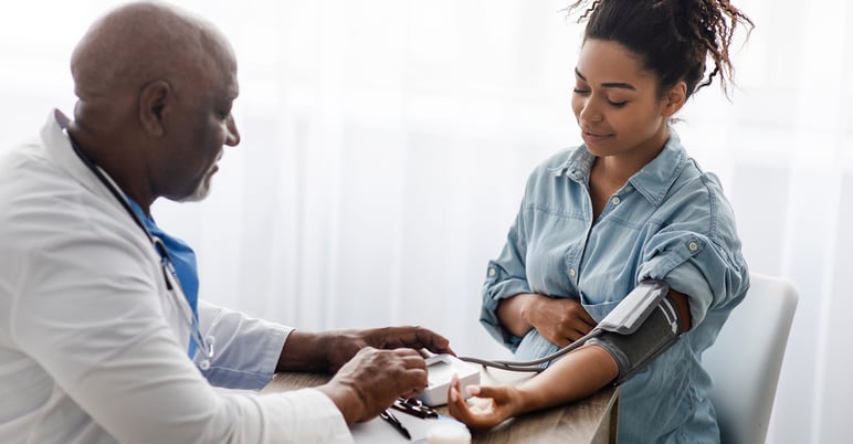 woman with her medical provider checking her blood pressure