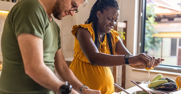 pregnant couple making a healthy meal together in the kitchen