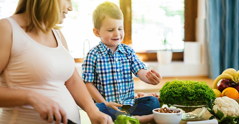 pregnant woman cooking with her toddler