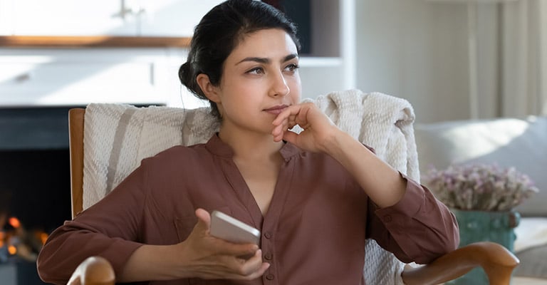 woman thinking while holding her phone