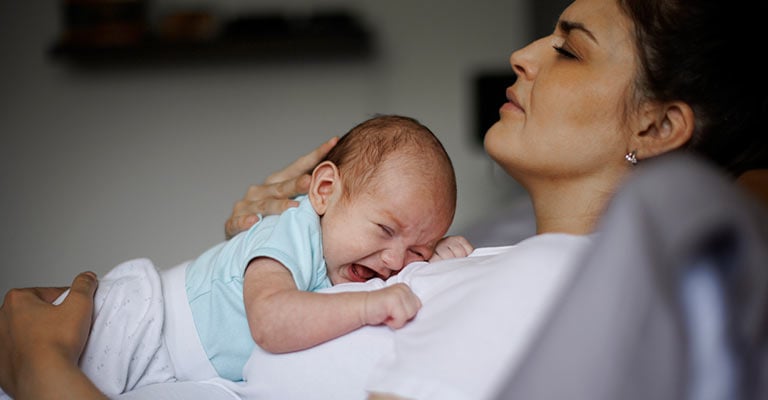 crying newborn resting on mother