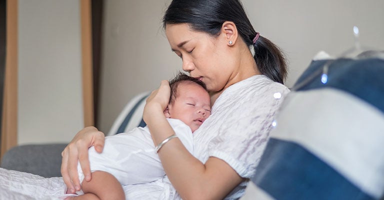 woman cuddling newborn