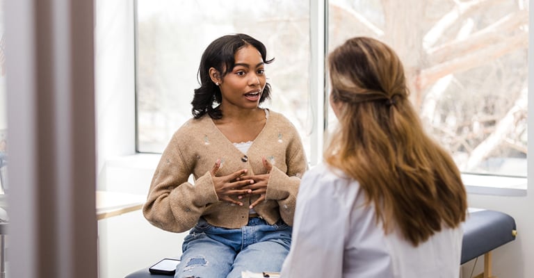 young woman in exam room talking with provider