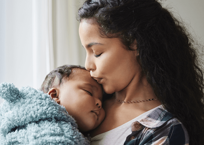 mother giving her baby a kiss on the forehead