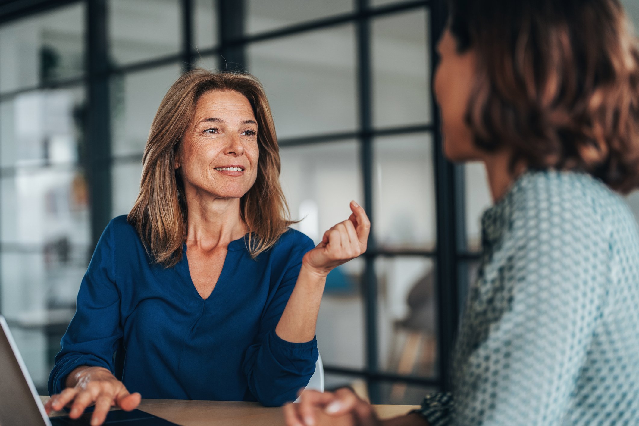 Two women having a focused and friendly conversation at a desk