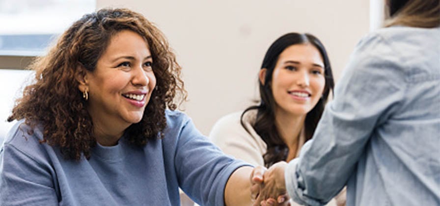 woman shaking hands in the office while seated with new colleagues