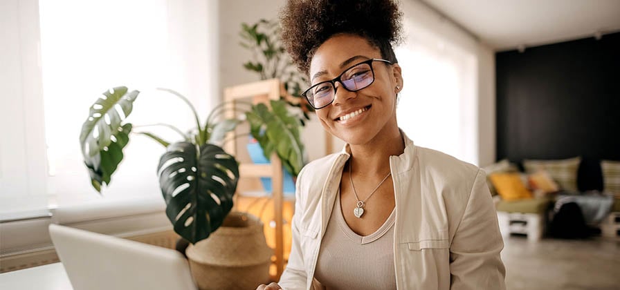 smiling woman with glasses working on laptop