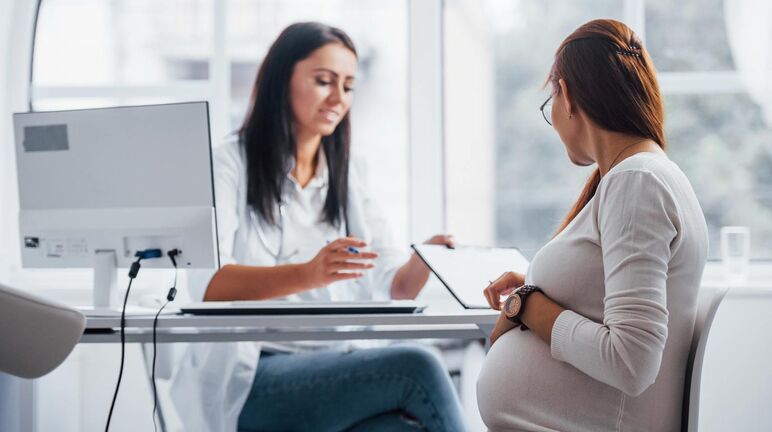 pregnant woman seated in consultation with medical provider