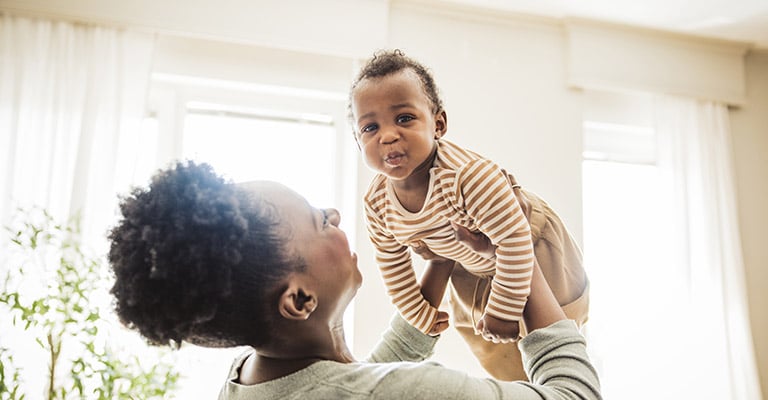 adult lifting a happy baby up