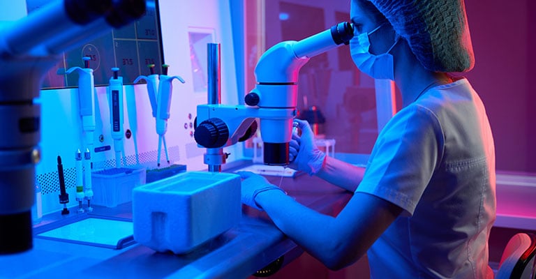 lab tech looking through microscope