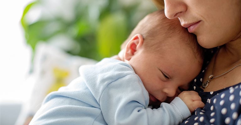 closeup of newborn resting on mother