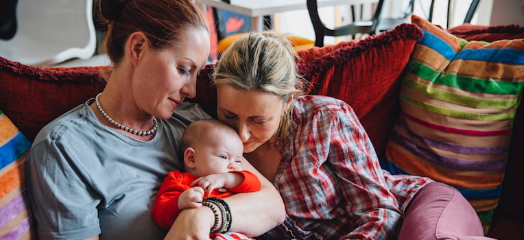 same-sex female couple holding their baby