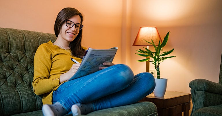 woman jotting notes while seated on the couch