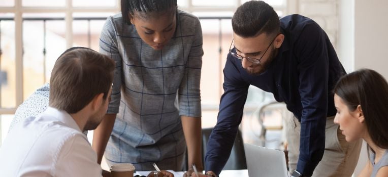 group of colleagues huddled over conference table