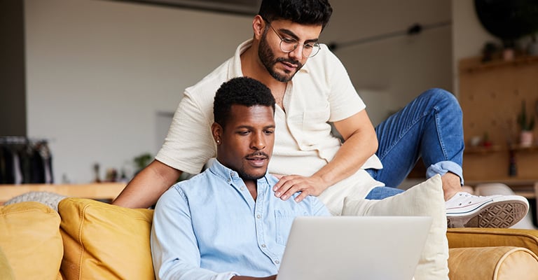 two men searching for information on laptop