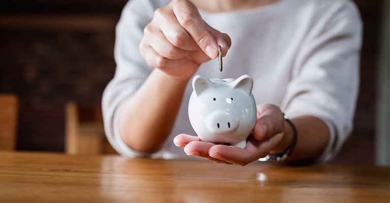 hand dropping a coin into a piggy bank