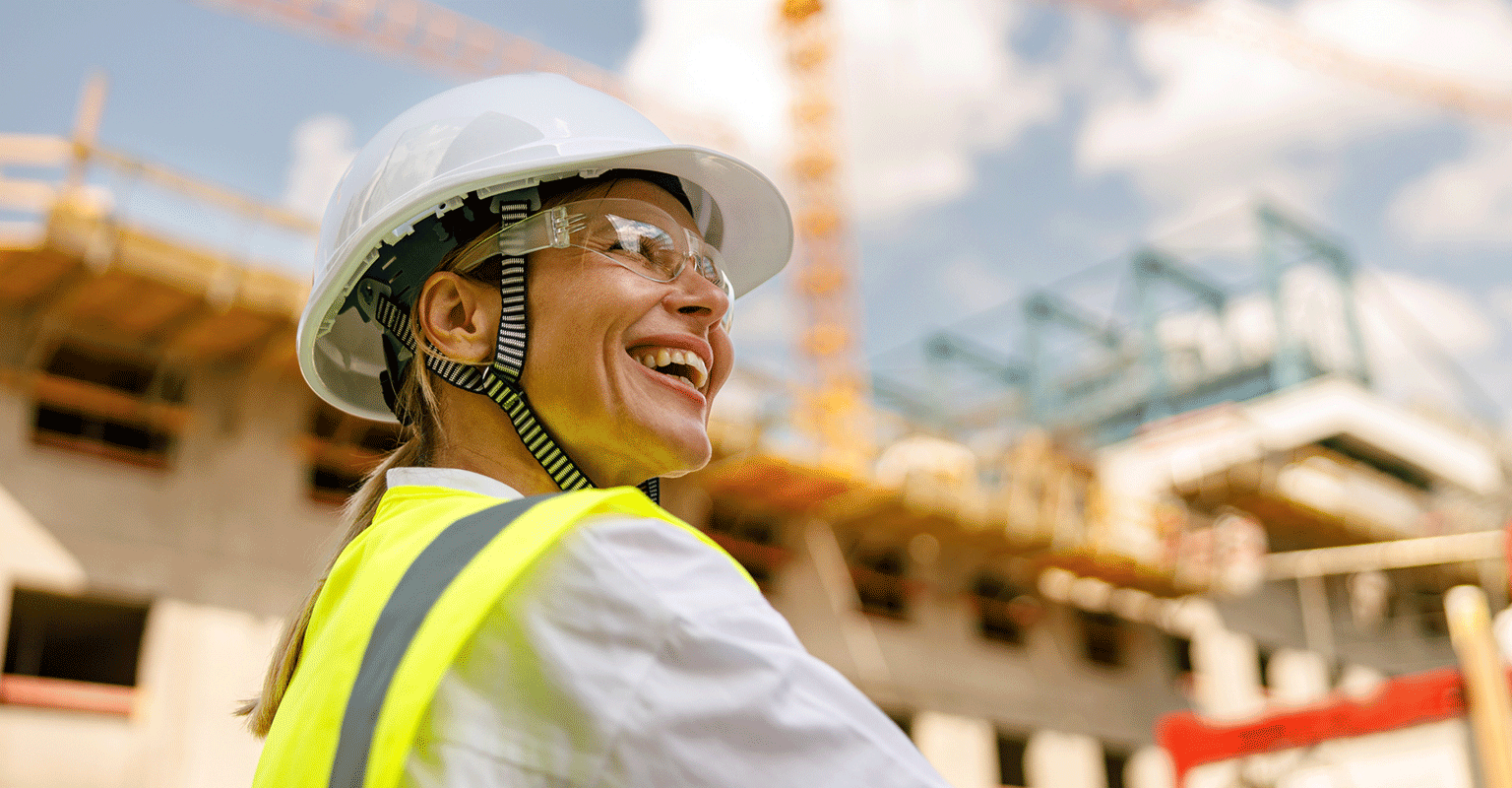 smiling woman in hard hat and construction vest
