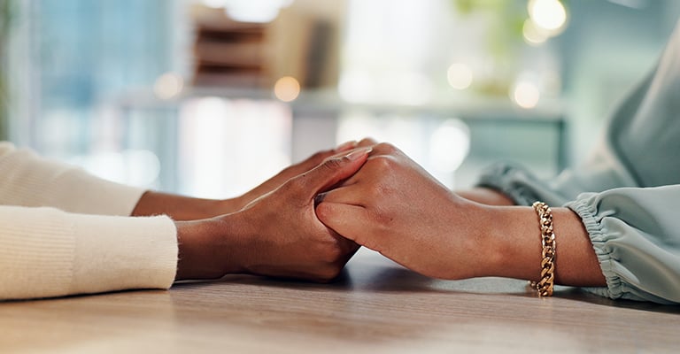 a pair of hands holding another person's hands in support