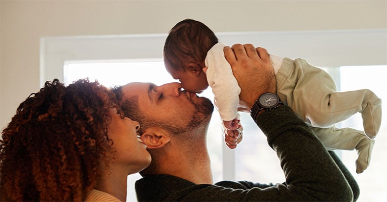 happy parents with the father holding a newborn in the air