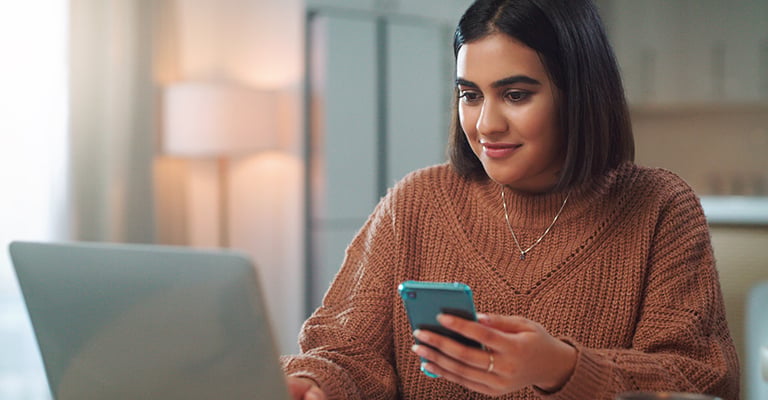 woman researching on phone and laptop