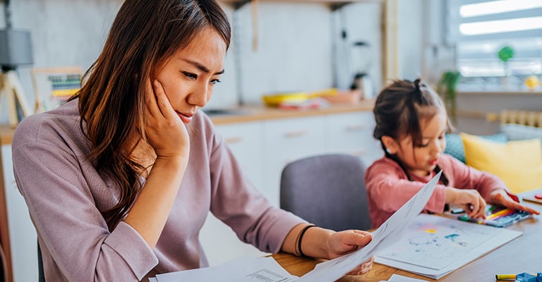 woman at table contemplating health plans while seated next to her toddler