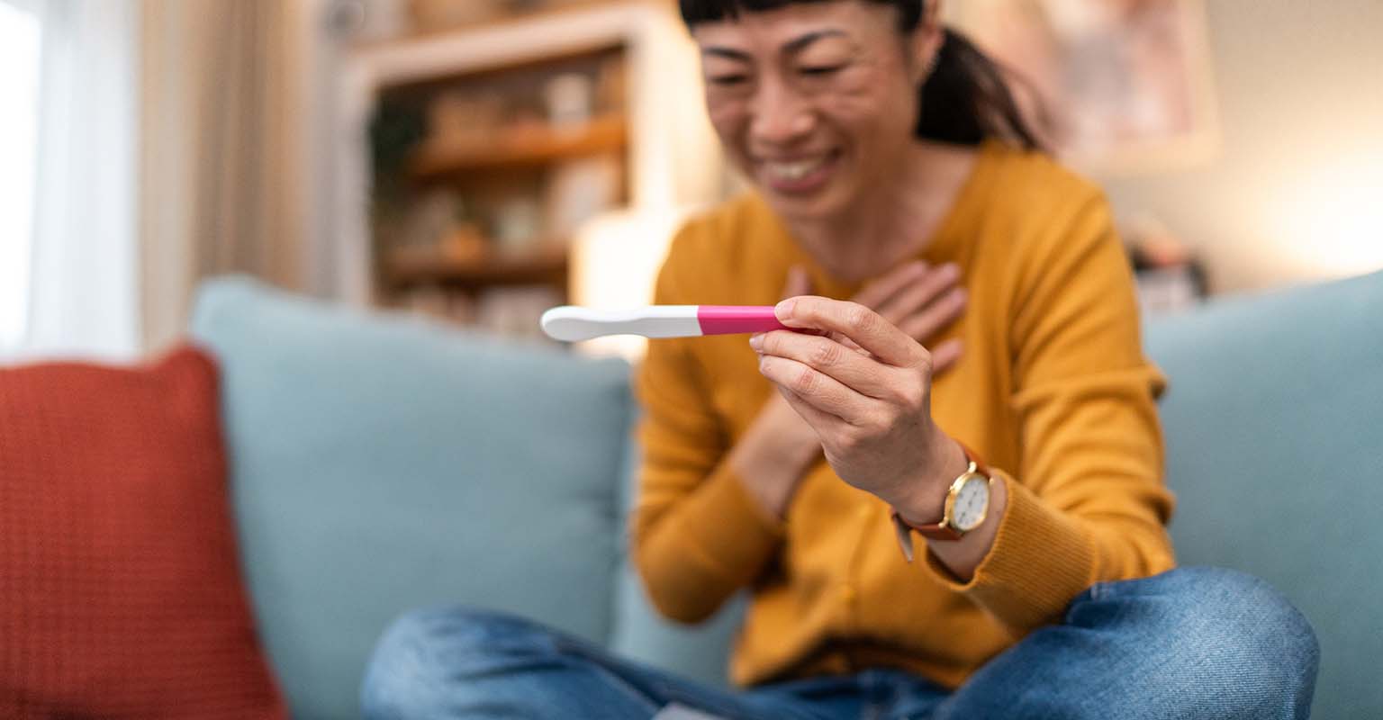 joyful woman looking at a pregnancy test