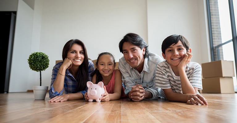 happy family resting on their stomachs with a piggy bank