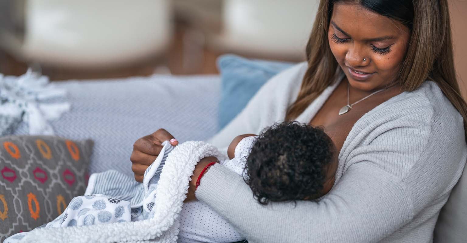 seated nursing mother looking at her newborn