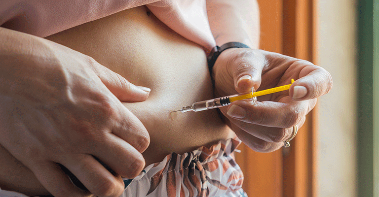 woman injecting IVF medication into her stomach
