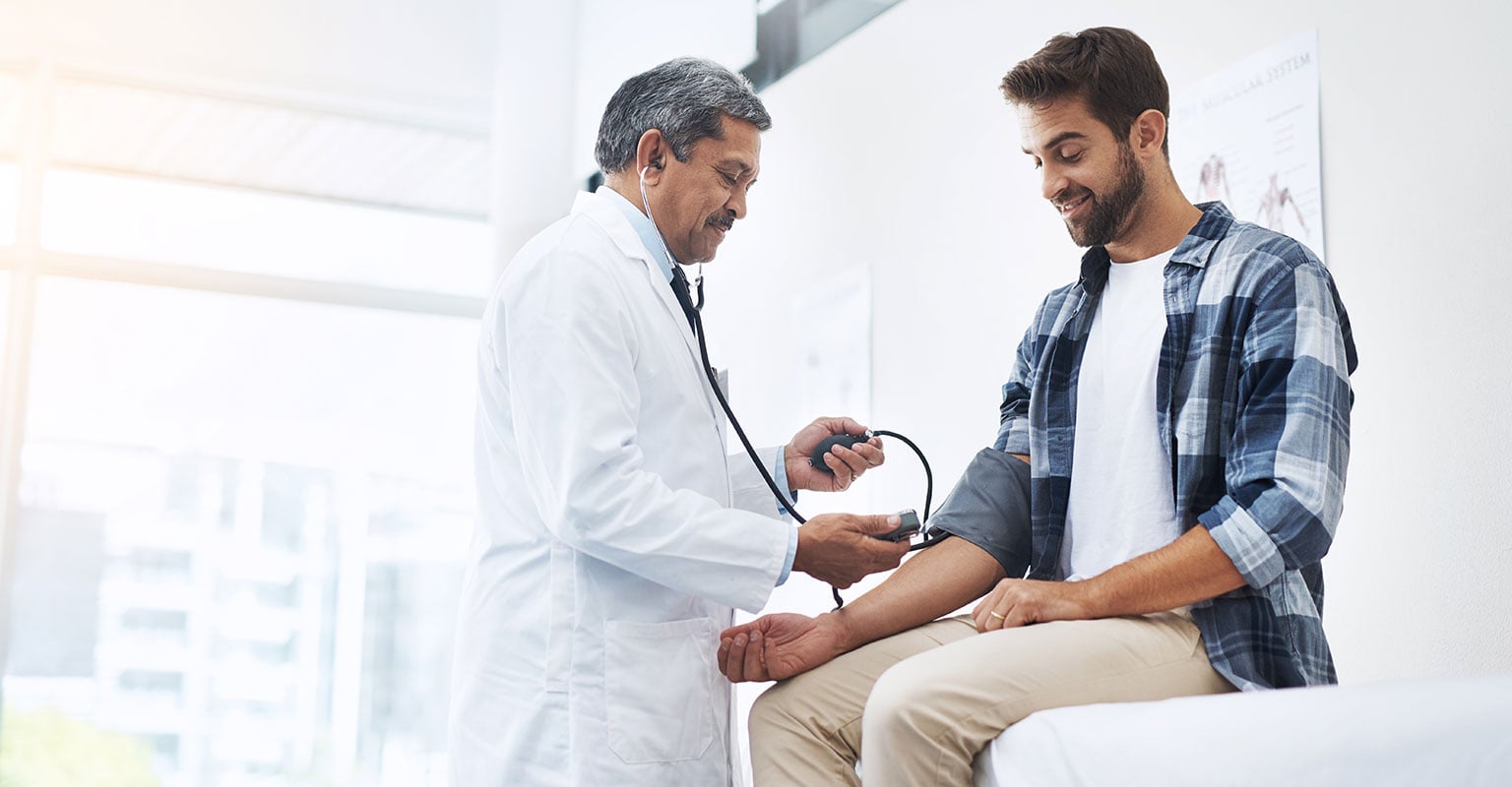 medical provider measuring his male patient's blood pressure