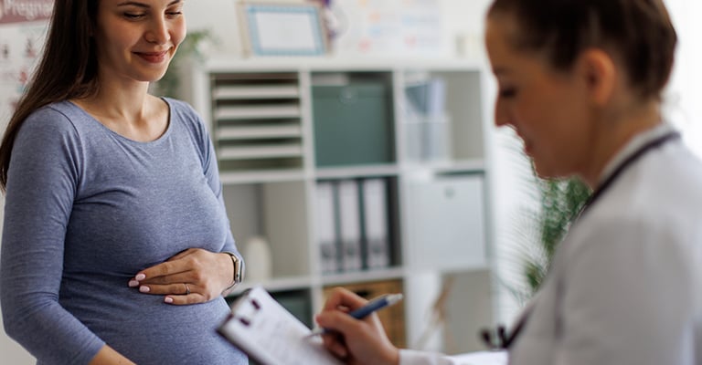 provider jotting notes during an appointment with pregnant woman