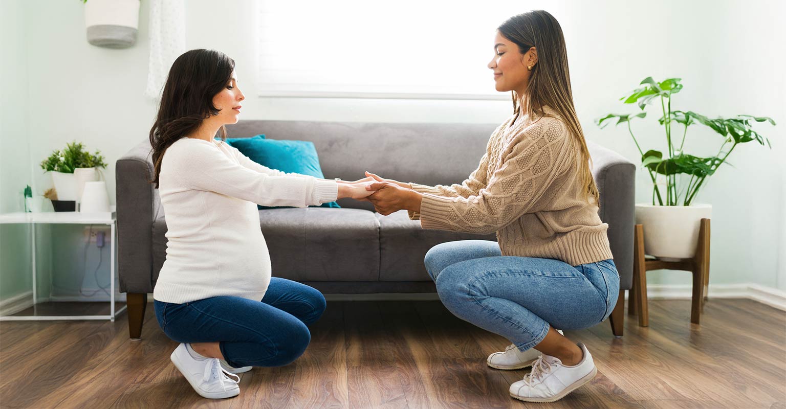 pregnant woman squatting in an exercise assisted by doula