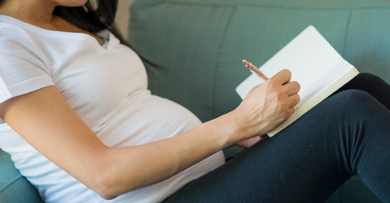 pregnant woman making a list in her notebook