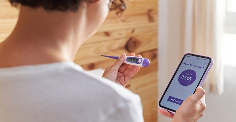 woman looking at a pregnancy test and her phone