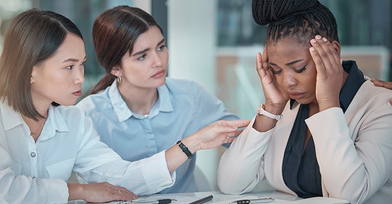 people at work comforting stressed colleague