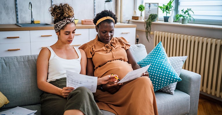 pregnant woman reviewing paperwork on couch