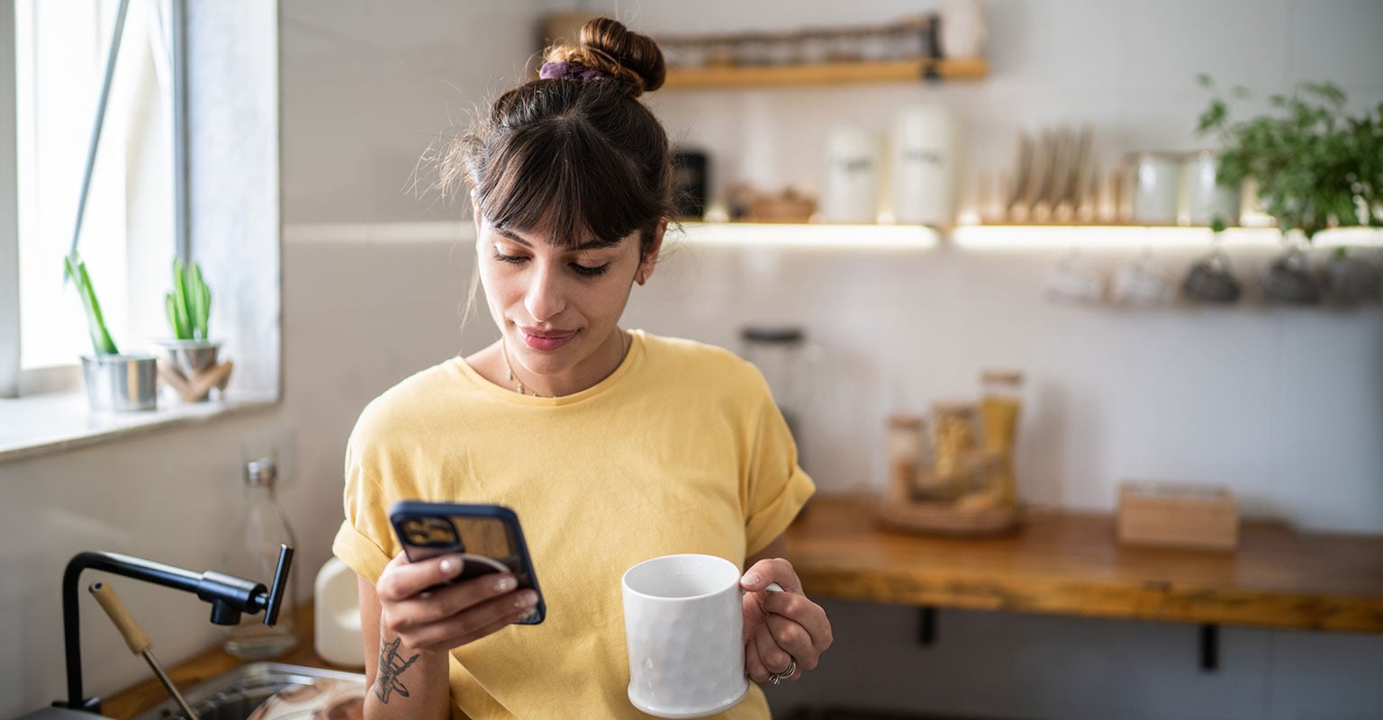 woman holding a cup of coffee and her phone