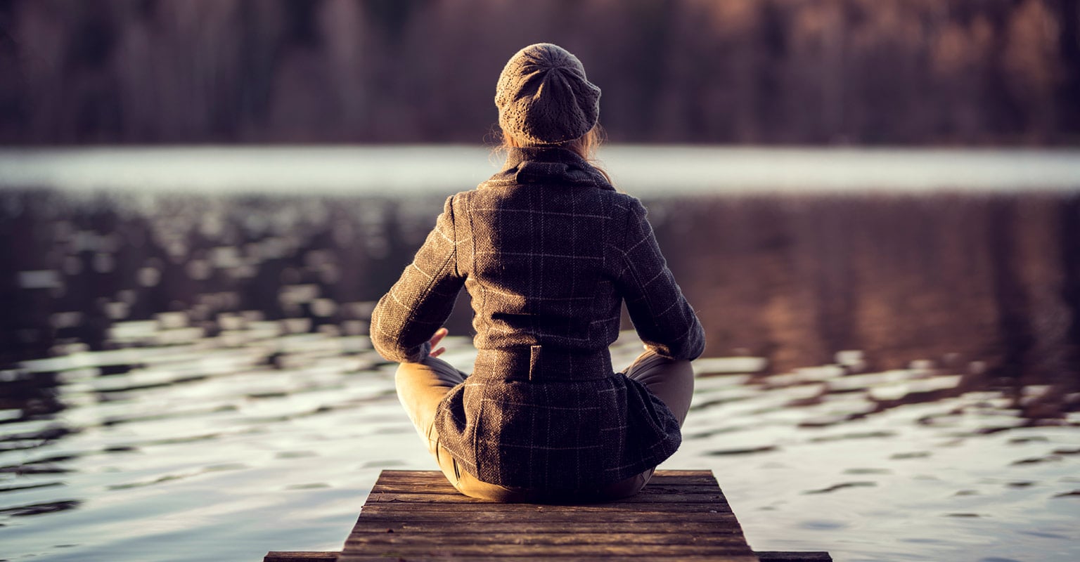woman seated on a dock looking over the water