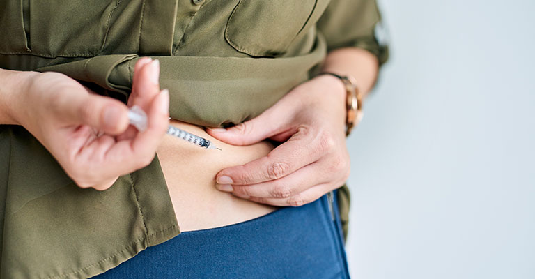woman injecting IVF medication into her stomach