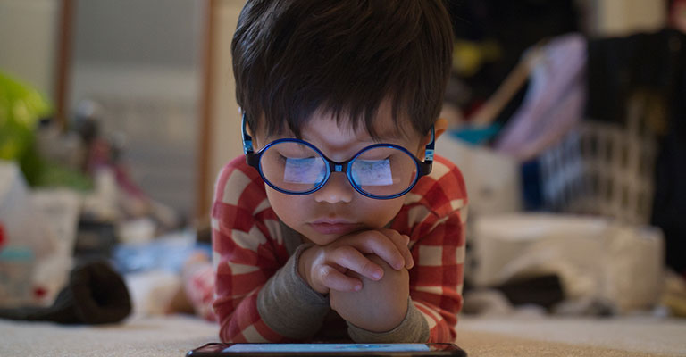 young child with glasses looking at a screen